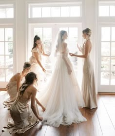 bridesmaids helping the bride put on her wedding dress