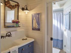 a bathroom with a sink, mirror and blue cabinet in it's center area