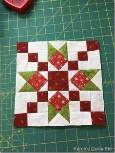 a piece of quilted fabric sitting on top of a cutting board next to a red heart