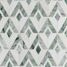 a white and green tiled wall with diamond shaped tiles on the bottom, in an irregular pattern