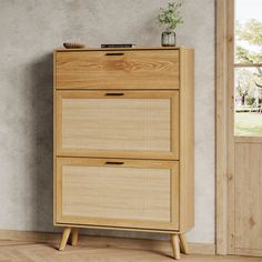 a wooden cabinet with two drawers in front of a window and a potted plant on top