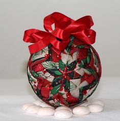 a christmas ornament with red ribbon and bow on top of some white balls