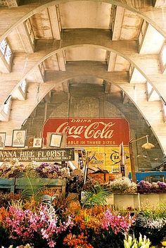 the inside of a building with many different flowers and signs on the side of it