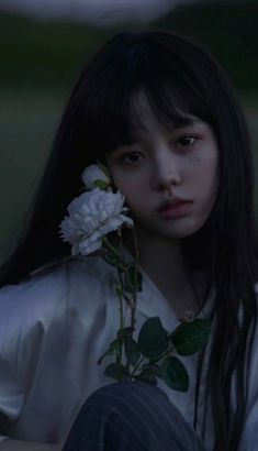 a woman with long black hair holding a flower