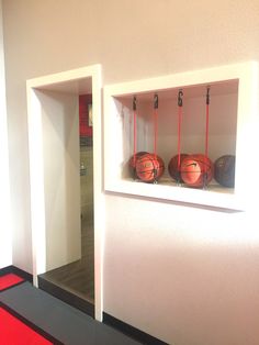 the basketballs are lined up on the wall in the room with red mats and hooks