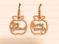 two wooden earrings with words on them and an apple hanging from the ear hooks that say,