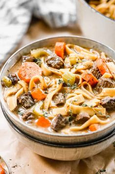 a bowl of beef noodle soup with carrots and parsley