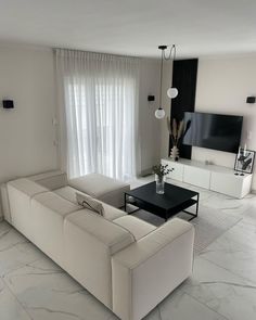 a modern living room with marble floors and white walls, including a black coffee table