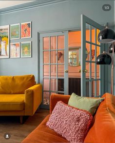 a living room with orange couches and pictures on the wall above them in different colors