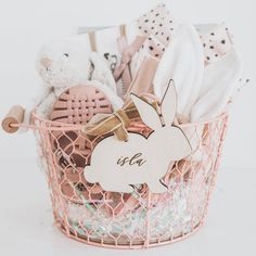 a pink basket filled with baby's items on top of a white table next to a teddy bear