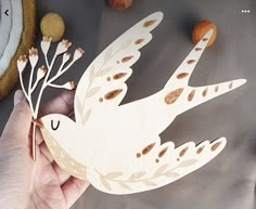 a hand holding a wooden cutout of a bird with leaves and acorns