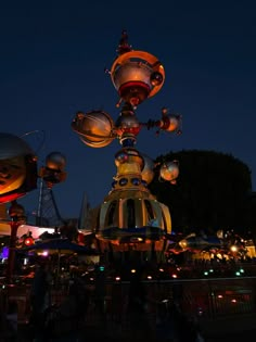 an amusement park lit up at night with lights on the top and bottom of it