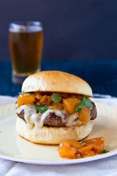 a cheeseburger on a plate next to a glass of beer