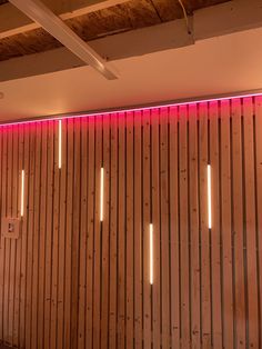 a room with wooden walls and pink lights on the wall, along with wood slats