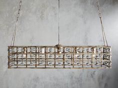 a chandelier hanging from the ceiling in front of a concrete wall with chains on it