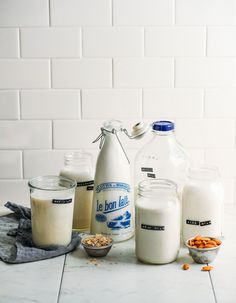 milk and cereals are sitting on the counter in front of a white tile wall