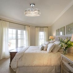 a bedroom with a chandelier hanging from the ceiling and two lamps on either side of the bed