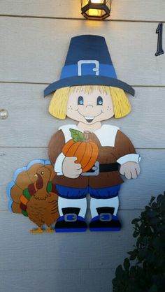 a sign with a scarecrow holding a pumpkin and a turkey on the side of a building