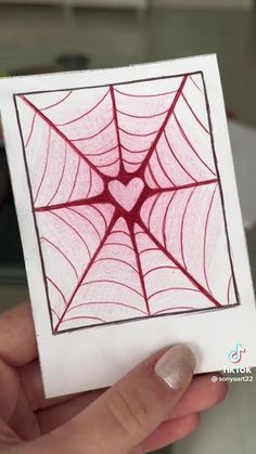 a hand holding up a drawing of a spider web