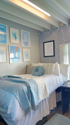 a bed sitting in a bedroom next to a window with pictures on the wall above it