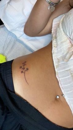 a woman laying in bed with her stomach covered by a flower tattoo on her lower back