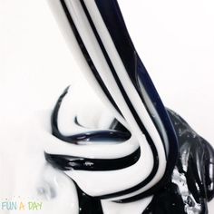 a black and white vase with liquid pouring out of it's sides, in front of a white background