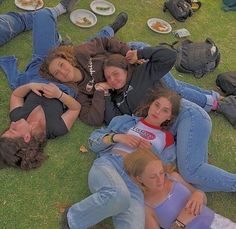 several people laying on the grass with plates of food