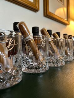 there are many glasses lined up on the table with wine bottles in them and one is empty