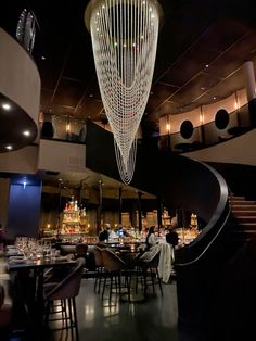 the interior of a restaurant with many tables and chairs in front of a spiral staircase