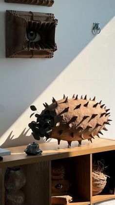 a hedgehog sculpture sitting on top of a wooden shelf in front of a white wall