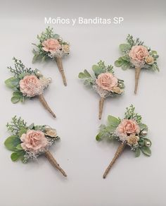 six boutonnieres with pink flowers and greenery are arranged on a white surface