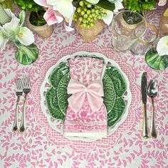 a pink and green place setting with flowers