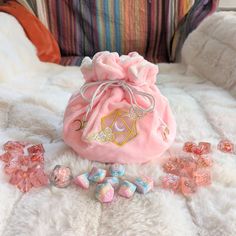 a pink bag filled with candy sitting on top of a white fur covered bed next to a pile of candies