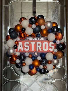 a houston astros ornament hangs on the front door to decorate it's wreath