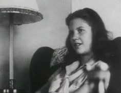 black and white photograph of a woman sitting in a chair with a lamp behind her