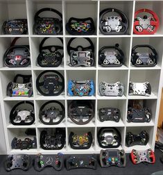 many different types of video game controllers in a storage unit with white shelving behind them