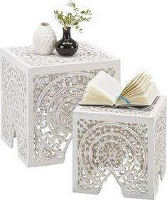 two white side tables with books and vases on each end table, one has an open book in front of the other