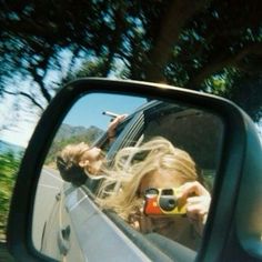 a woman taking a selfie in the side mirror of a car