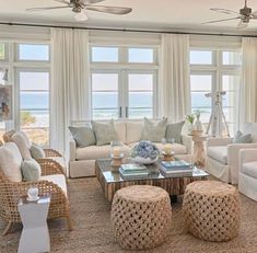 a living room filled with lots of furniture and large windows overlooking the ocean in front of them