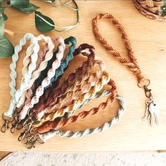 a bunch of bracelets are sitting on a wooden table next to some leaves and beads