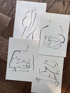 four different drawings on white paper sitting on top of a wooden floor