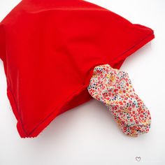 a red pillow with a flowered bow tie on it's side, laying next to a red pillow