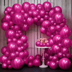 a table topped with a cake covered in pink balloons