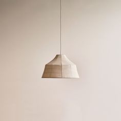 a white lamp hanging from a ceiling in a room with beige walls and flooring