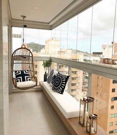 a balcony with a swing chair and pillows on the floor next to a large window