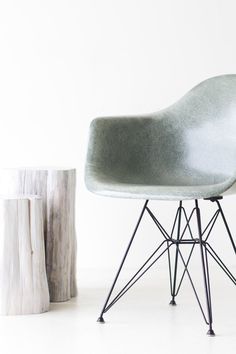 a grey chair sitting next to a wooden stump on top of a white flooring