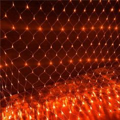 some lights that are on the ground in front of a mesh fence with an orange glow