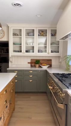 a kitchen with wooden floors and white counter tops on the wall, along with cabinets that have glass front doors