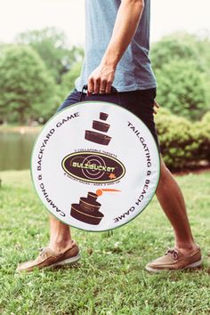 a man holding a frisbee in his hand while walking through the grass with trees behind him