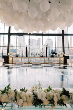 balloons are hanging from the ceiling in front of tables with chairs and vases filled with flowers